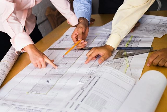 Two professionals examining construction blueprints to review project details and scope of work.