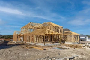 Custom home under construction showing unfinished structural work and site conditions that can contribute to hidden building costs.