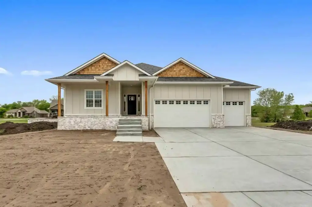 Newly built custom home with unfinished driveway and landscaping showing exterior completion costs often excluded from construction estimates.