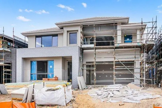 Modern residential house undergoing construction with exterior scaffolding and unfinished building work.