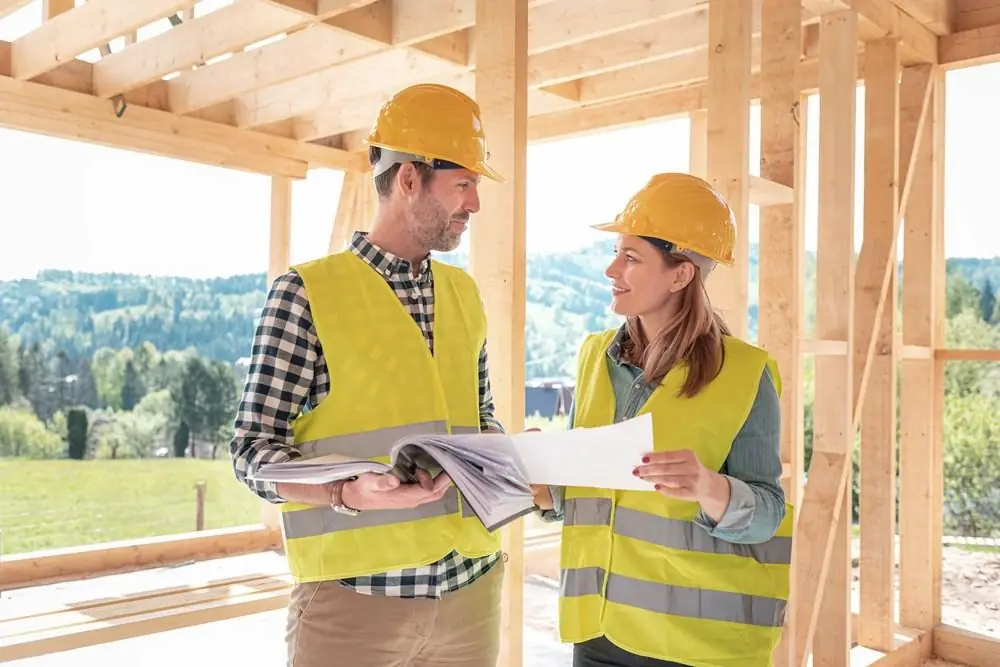 Construction professionals reviewing building plans together while coordinating work on a residential construction project.