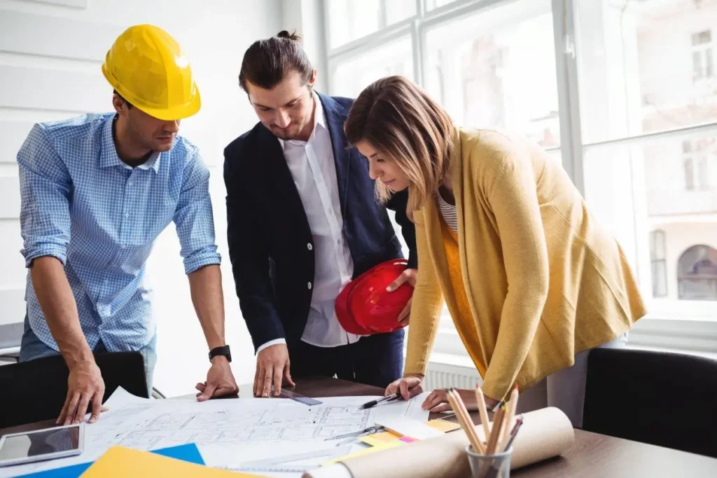 Construction professionals reviewing residential building plans and discussing contractor proposals before construction.